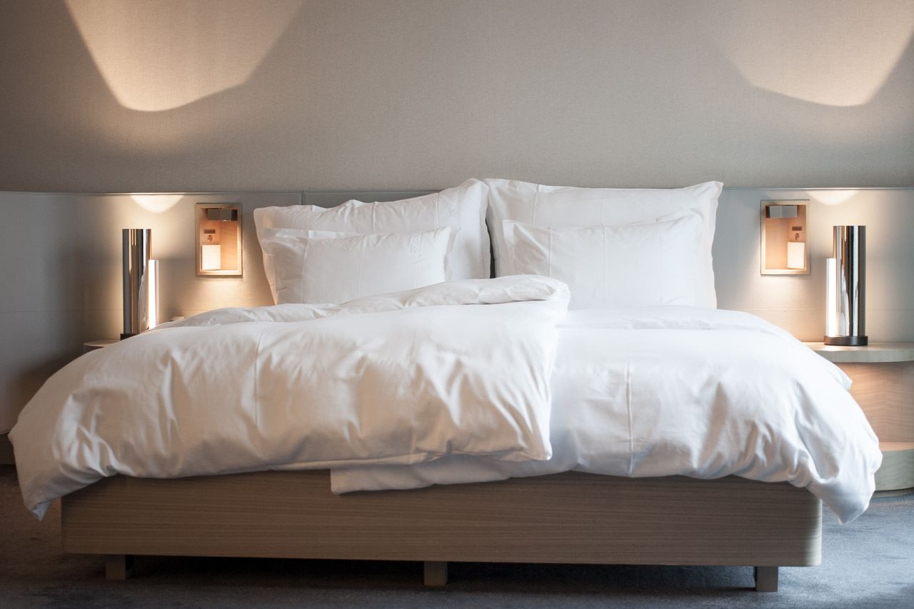 Elegant hotel room with comfortable bedding and modern lighting fixtures.